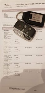 Jaguar car key placed on a printed vehicle service history document