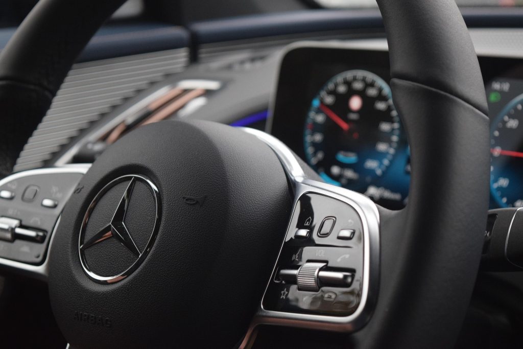 Close-up of a Mercedes steering wheel with digital instrument display and dashboard controls